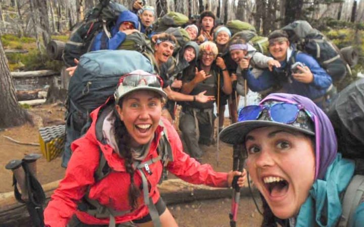a group of students smile excitedly while backpacking on an outward bound trip